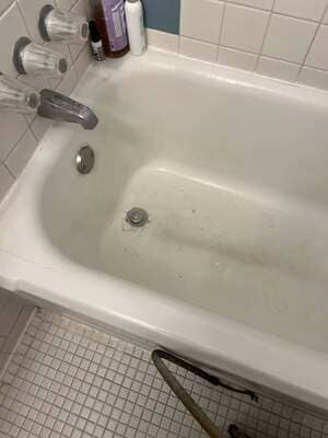 Technician inspecting a bathtub for leaks