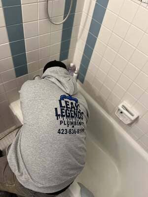 Licensed plumber repairing bathtub plumbing