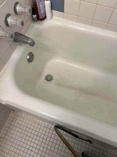 Technician inspecting a bathtub for leaks